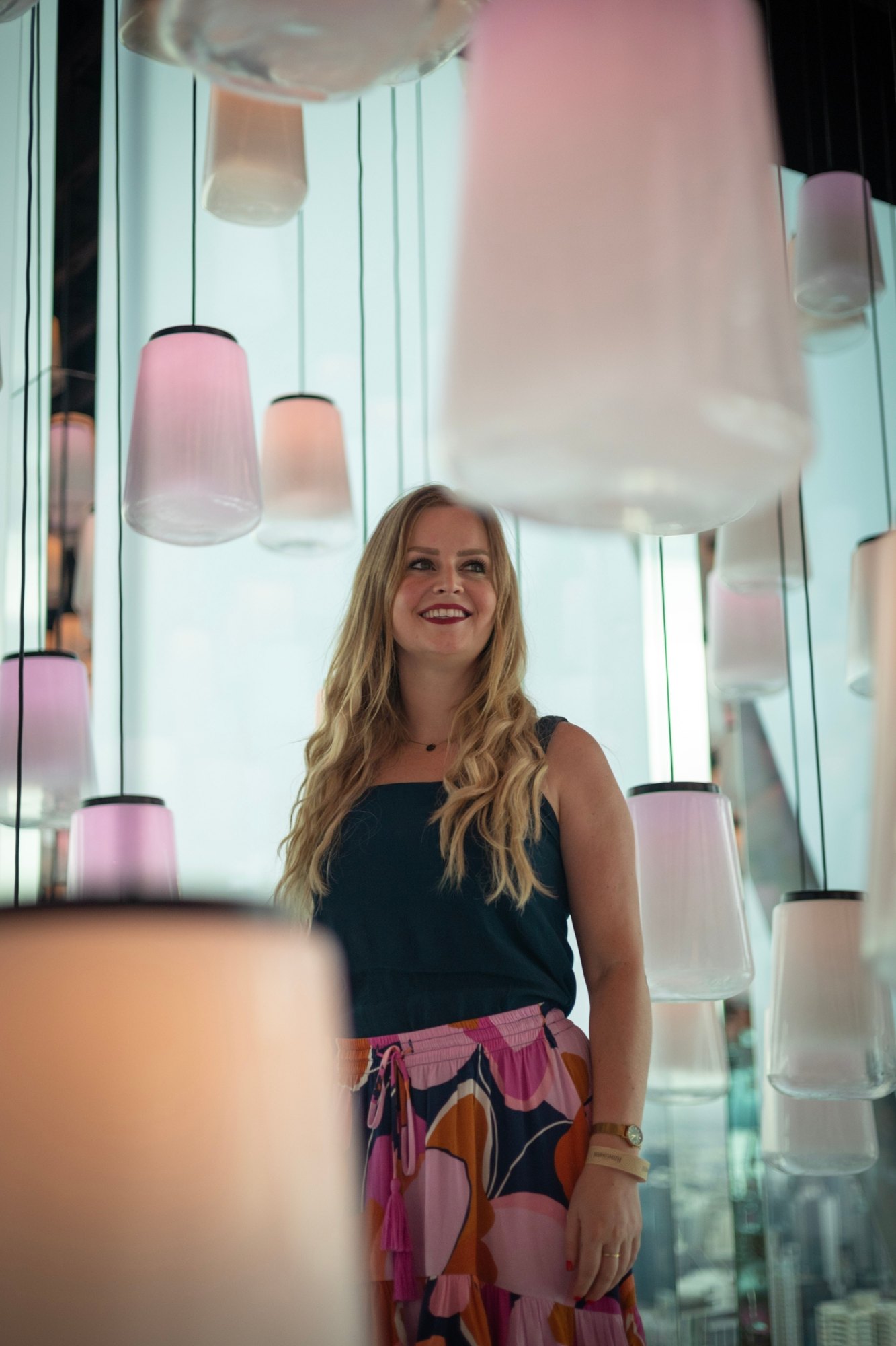 Jeanella looking up among glowing pastel pendant lights